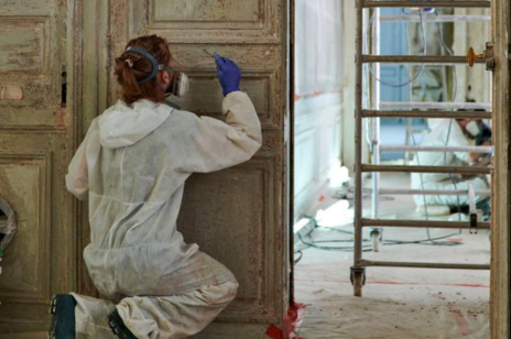 Hôtel de la Marine, restauratrice dégageant les couches de peinture les plus récentes appliquées sur des boiseries